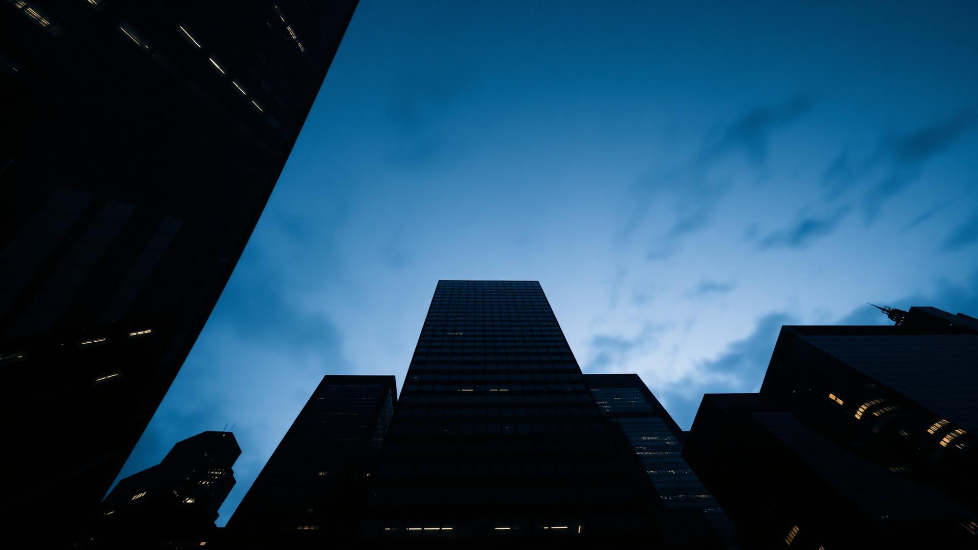 Corporate towers seen from below against a deep blue dusk sky